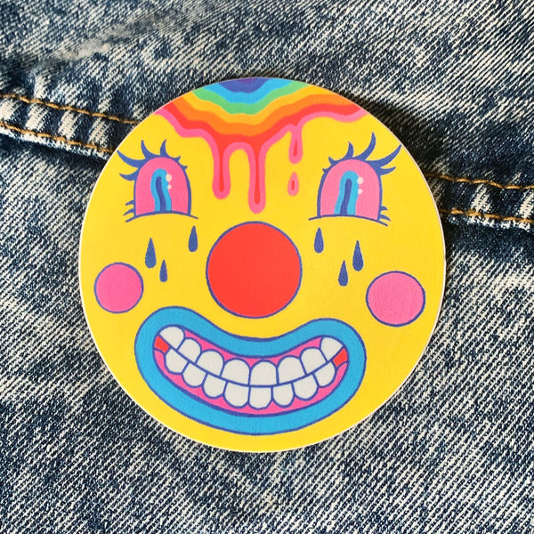 Circular sticker of a clown-like emoji with a dripping rainbow forehead. Art from Osseous Design by independent artist Makena Peet.