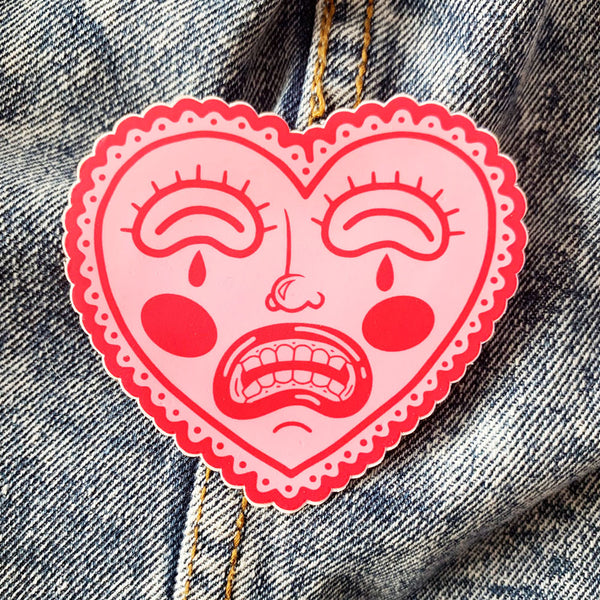 Crying, red heart-shaped face, vinyl sticker with matte finish. Scratch, water, and sunlight resistant. From Osseous Design by independent artist Makena Peet.
