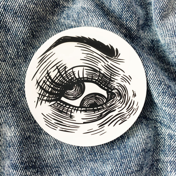Black and white vinyl sticker of an eye with two pupils in a matte finish. Scratch, water, and sunlight resistant. From Osseous Design by independent artist Makena Peet.
