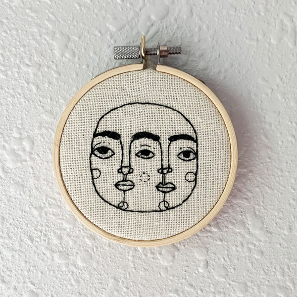 Two-sided face, hand embroidered on a wooden hoop. From Osseous Design by independent artist Makena Peet.